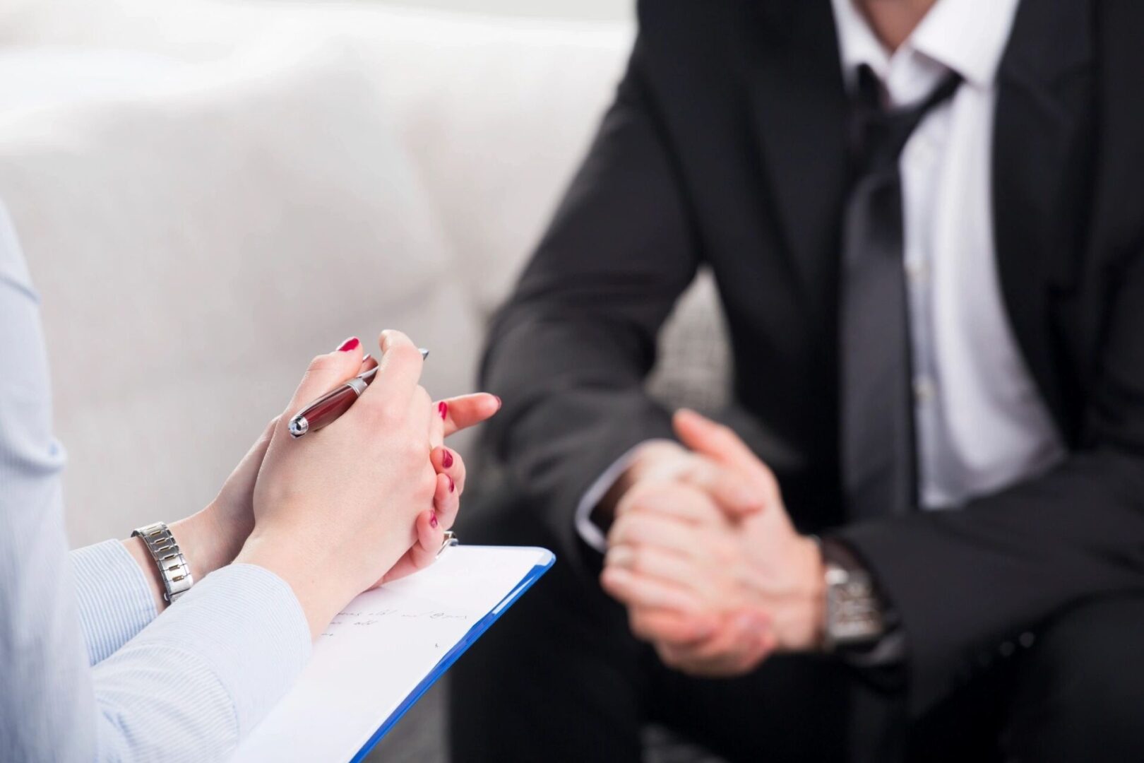 A business professional consulting with a client holding a clipboard.